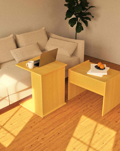Two wooden side tables in a living room with a laptop, mug, and fruit on top.